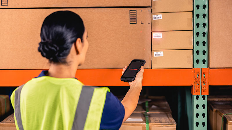 A woman using a Honeywell mobile computer in a warehouse